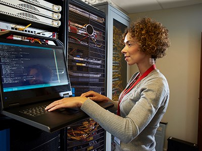 a female IT technician is editing the programme on the network server in a server room